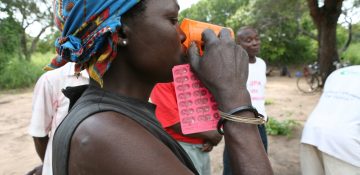 Een Mozambikaanse vrouw neemt haar medicijnen met water in                