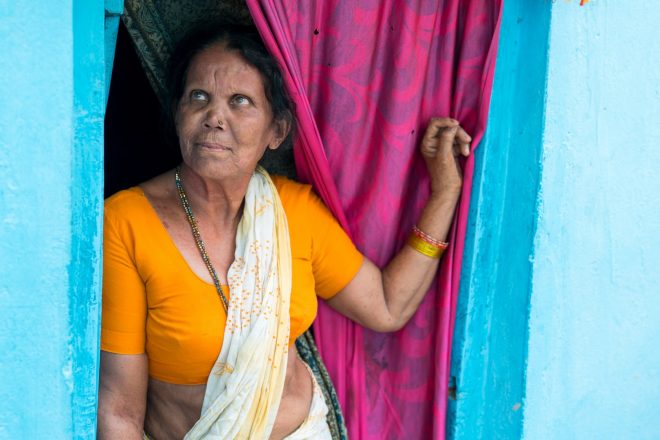 Een vrouw uit India staat tegen haar deurpost geleund